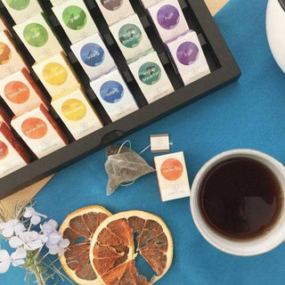 Presentación de Semper Tea con bolsitas de té, taza servida y rodajas de frutas secas.